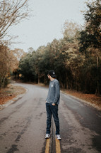 a man standing in the middle of a road and looking behind him 