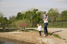 a mother and her kids feeding the ducks at a park 