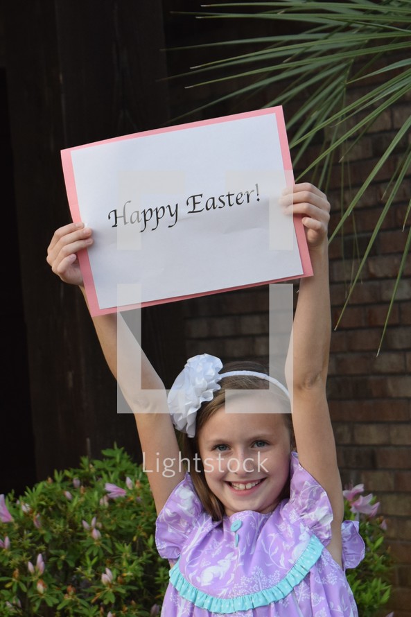 A little girl holding up a Happy Easter sign 