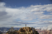 man standing on a peak surrounded by canyons 