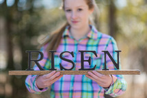 teen girl holding a Risen sign 