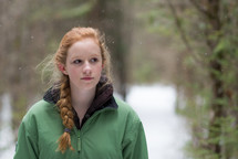 a teen girl in a winter coat standing outdoors in snow 