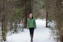 a teen girl in a winter coat standing outdoors in snow 