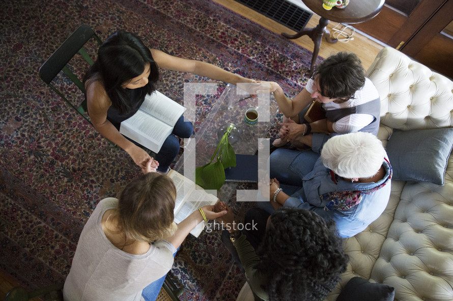 woman's group Bible study having a discussion and prayer in a living room 