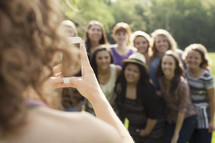 Teenage girl taking a picture of a group of young teen women.
