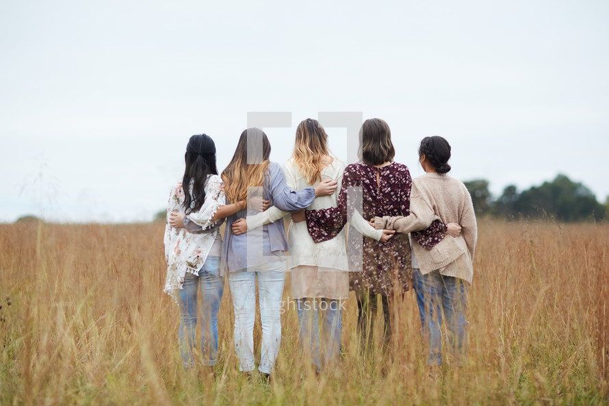 a group of young woman standing in a field 