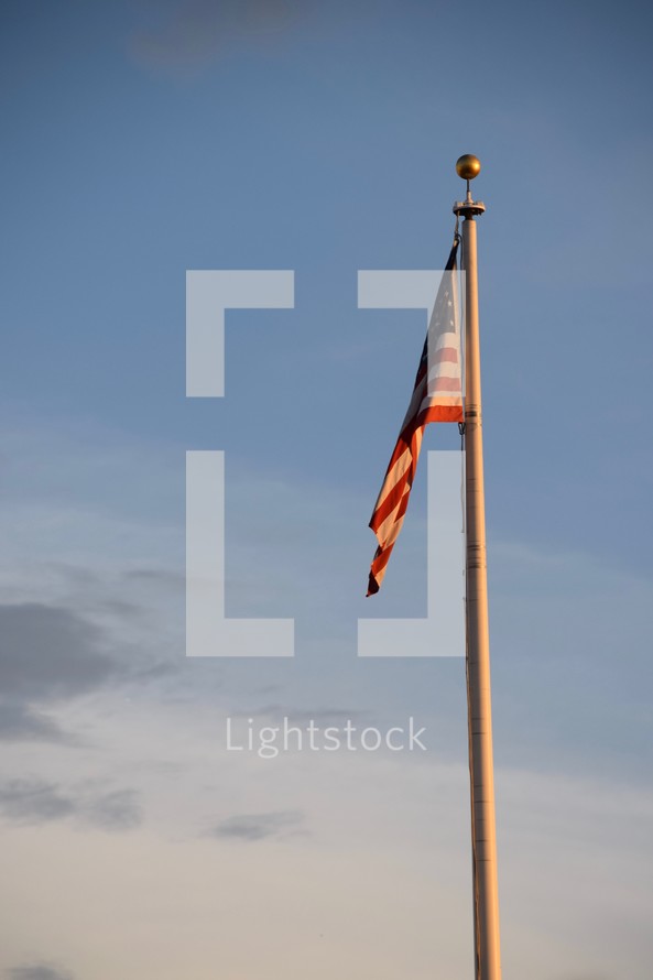 American flag on a flagpole at sunset 