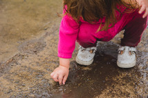 a toddler playing in mud 