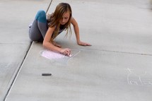 girl drawing a heart and church in sidewalk chalk 
