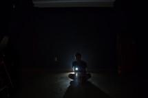 a man sitting with a flashlight 