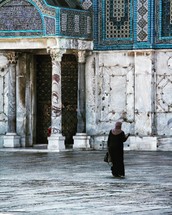 a muslim woman standing in front of a mosque 