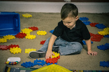 A little boy playing with plastic blocks.