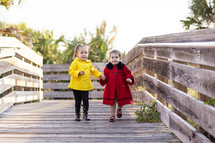 Sisters walking on a wooden bridge.