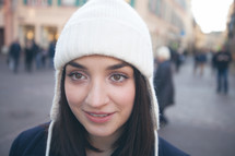 face of a woman standing outdoors in a winter hat and coat 