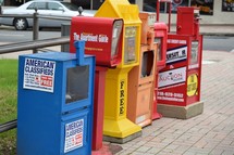 Newspaper vending machines on a city sidewalk 