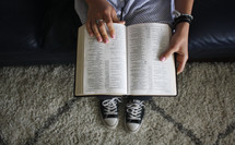 teen girl sitting on a couch reading a Bible 