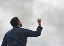 a man with a raised fist looking up to God 