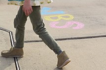 a child walking on a sidewalk with the word VBS in chalk 