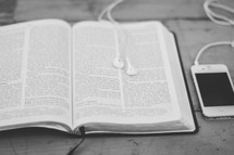 earbuds on the pages of a Bible and an iPhone 