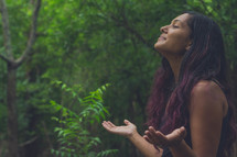 a woman praising God in a forest 