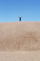 arms raised standing on sand dunes 