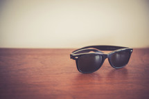 Wayfarer sunglasses on a wooden table.