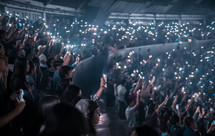crowds holding up cellphone lights at a concert 