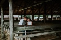 couple sitting in wooden pews outdoors 