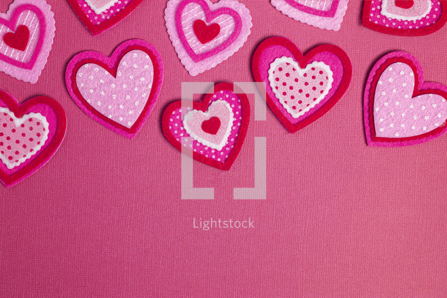 Simple Background with Felt Love Hearts on a pink background 