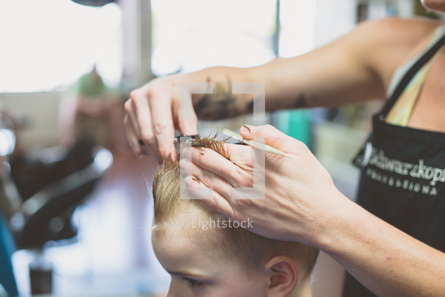 A woman cutting a little boy's hair.