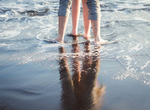 legs of a couple standing on a beach 