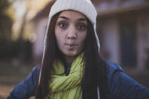 A young woman making a funny face wearing a white beanie