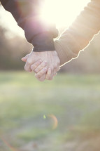Mature couple holding hands in sunlight.