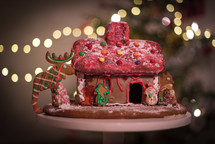homemade gingerbread house and bokeh Christmas tree lights 
