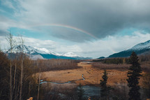 rainbow over snow capped mountains 