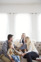 A family of four sits together on a couch.