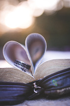 wedding bands in the pages of a Bible folded into the shape of a heart 