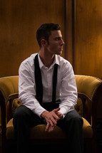 A man sitting in a chair with a loose tie 