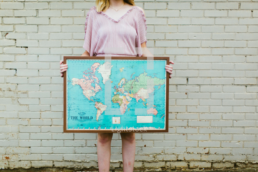 woman holding a framed world map 