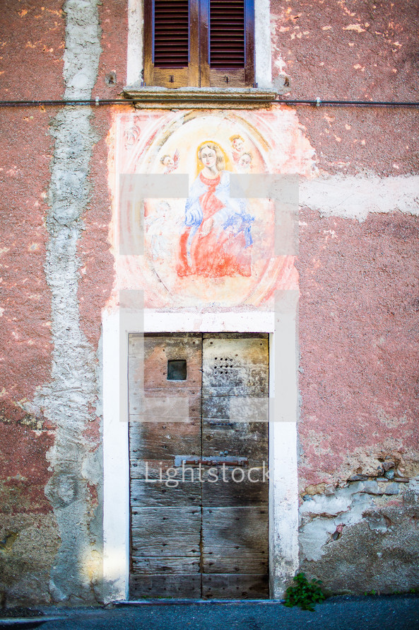 a weathered painting of Mary on an exterior wall in France 