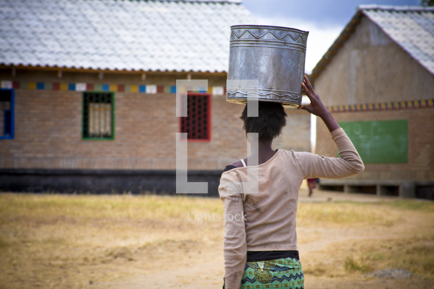 Woman carrying a metal bowl on her head