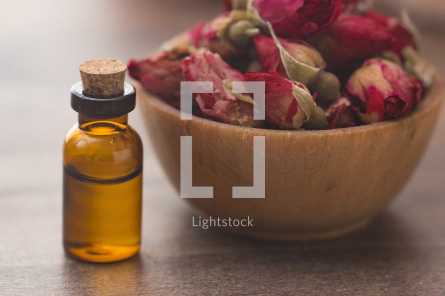 glass essential oil bottle and dried roses 