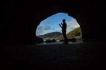 silhouette of a man with closed fists at the entrance of a cave 