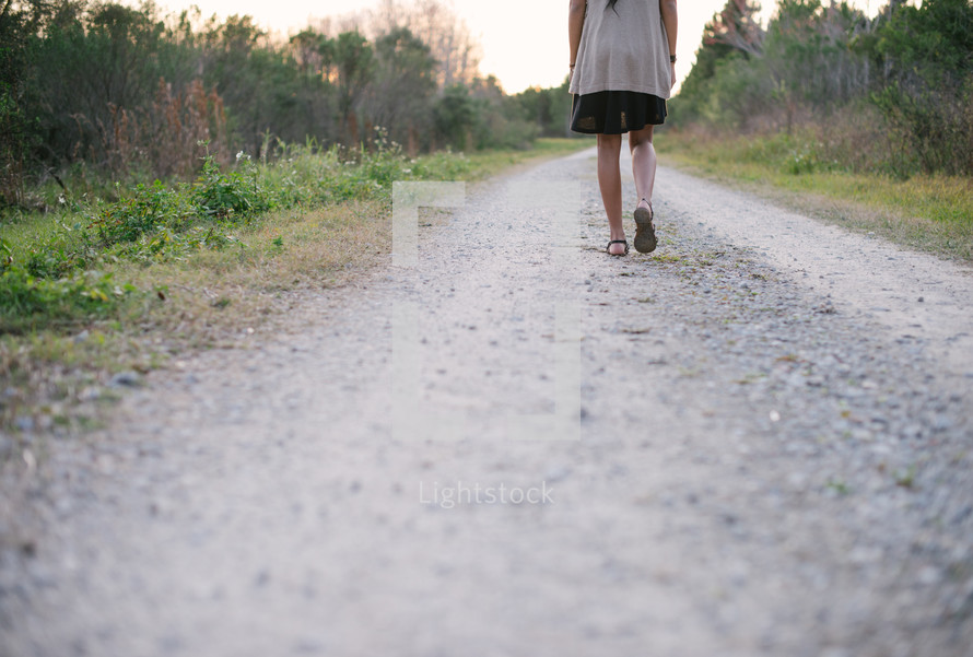 woman walking on a gravel road 