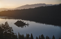 A lake right at the beginning of sunrise with mountains and trees in background