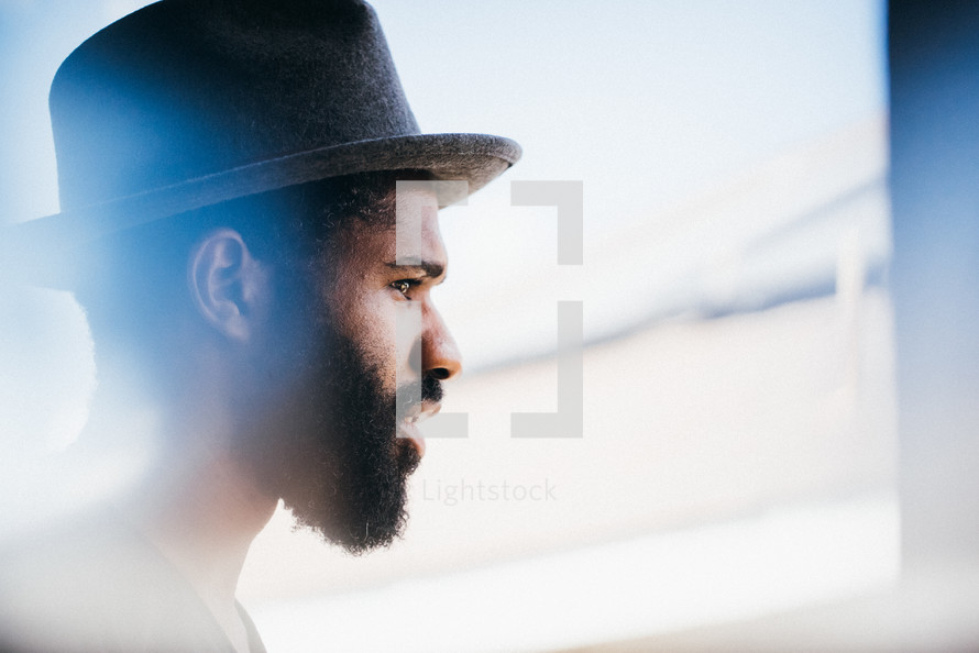 side profile of a man in a hat with a beard 