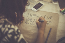 teens writing Bible verses on paper bags 