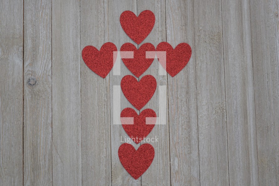 red hearts in the shape of a cross on a wood background 