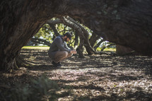 a man squatting under trees in prayer to God 
