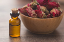 glass essential oil bottle and dried roses 